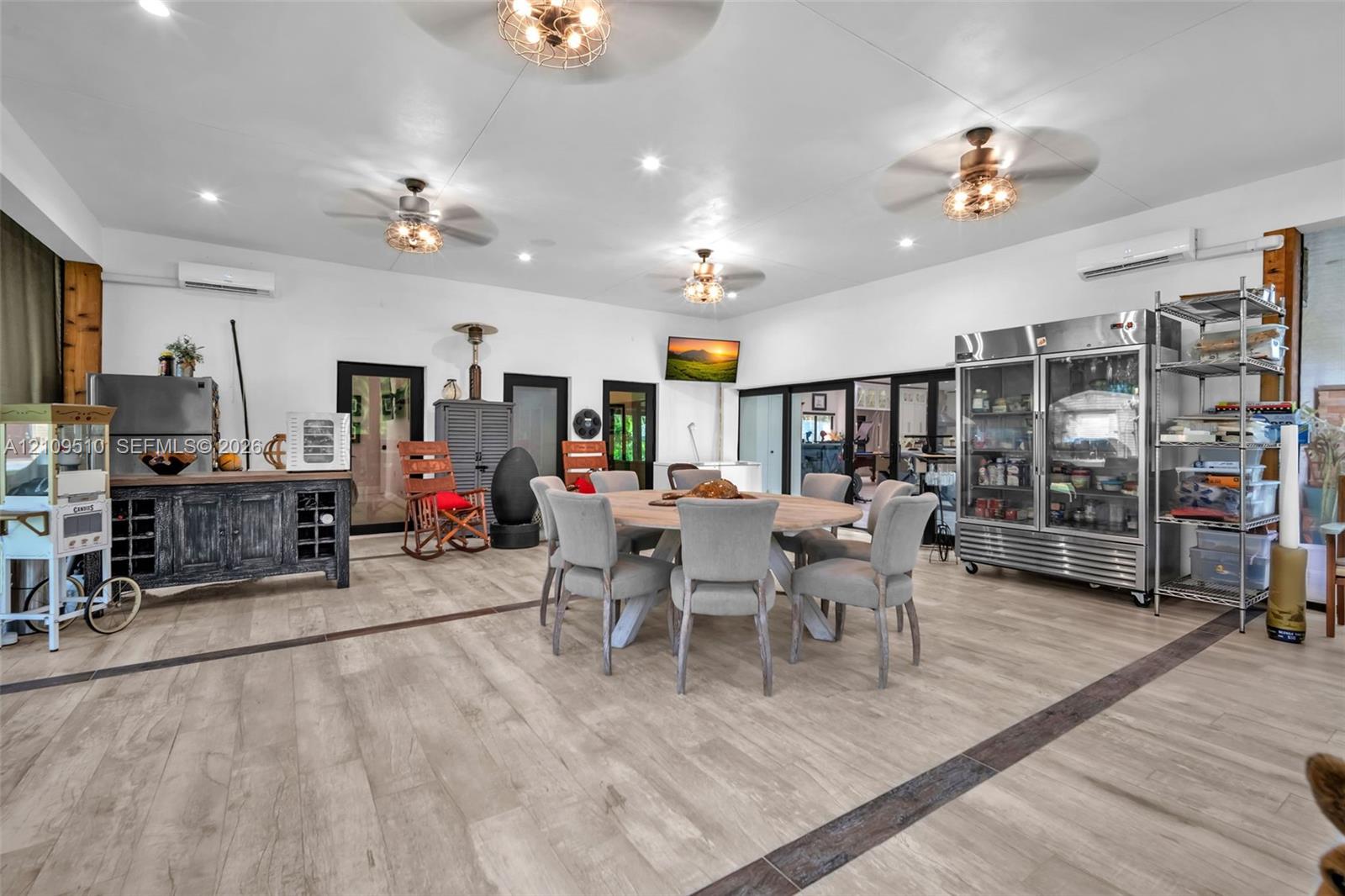 Open-concept area featuring wood-finish flooring, recessed lighting, multiple ceiling fans, and two wall-mounted ductless climate control units