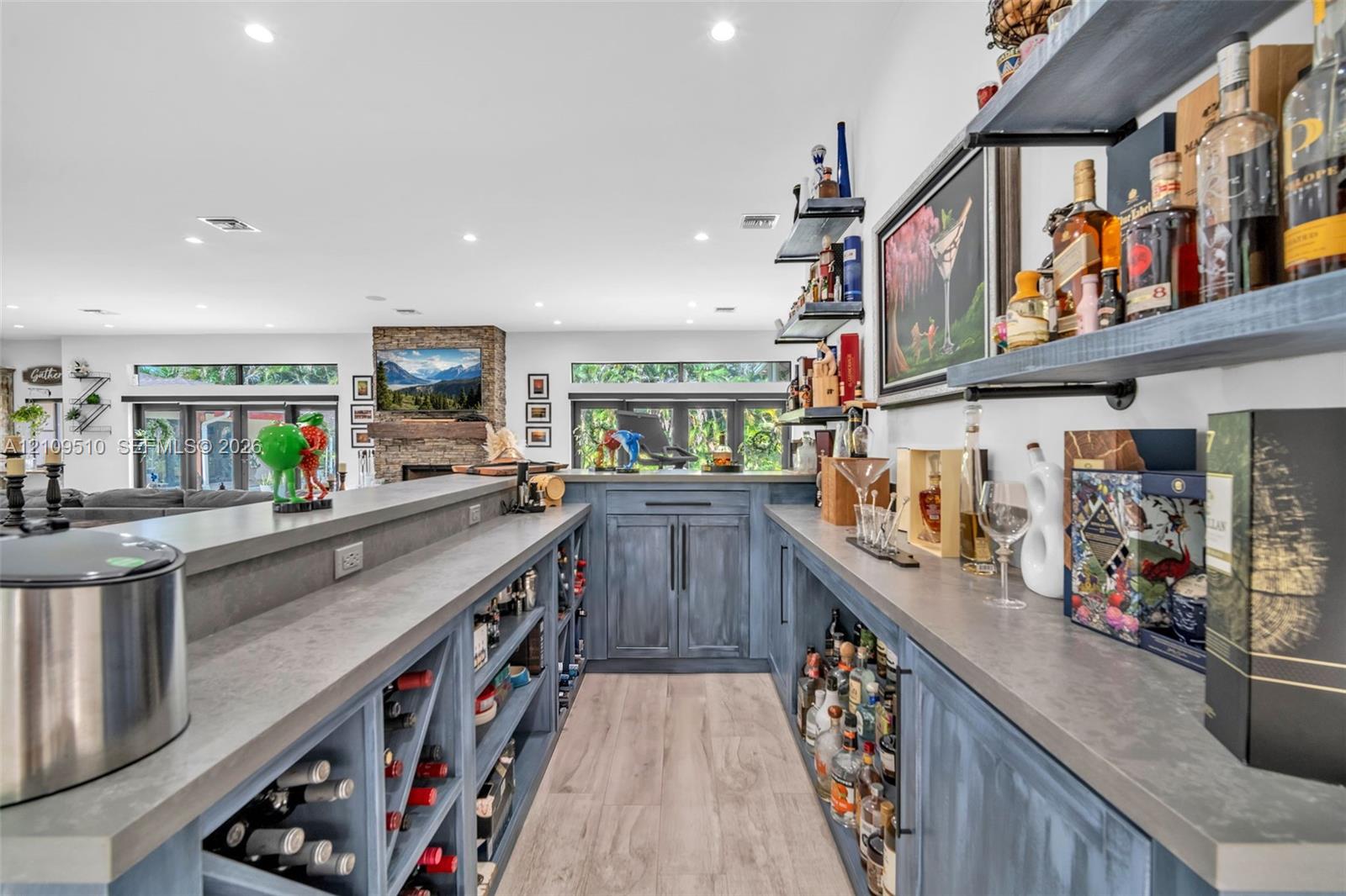 Custom built-in bar featuring stained wood cabinetry, stone countertops, integrated wine storage, and floating wall-mounted shelving with recessed lighting