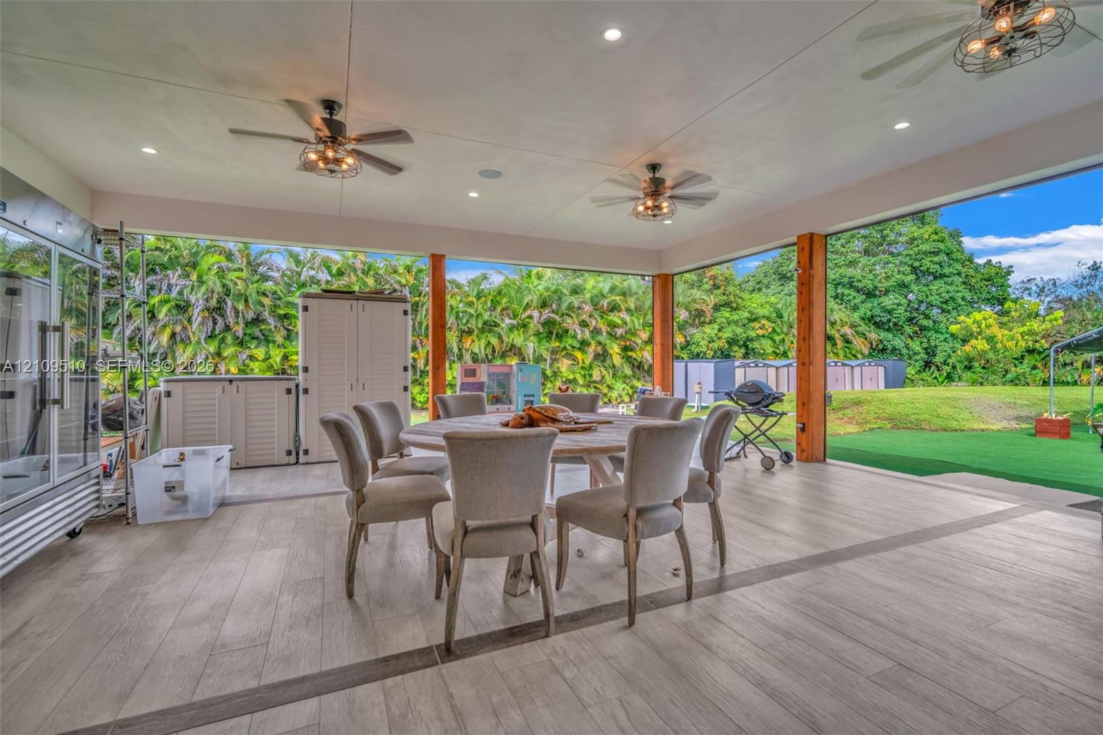 Covered patio featuring wood-finish flooring, recessed lighting, ceiling fans with integrated light fixtures, and structural support posts