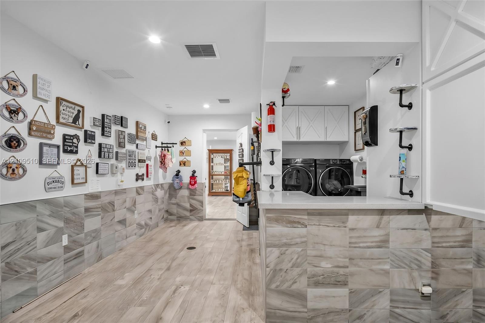 Utility area featuring wood-finish flooring, stone-tiled wall accents, recessed lighting, and white cabinetry with a quartz countertop