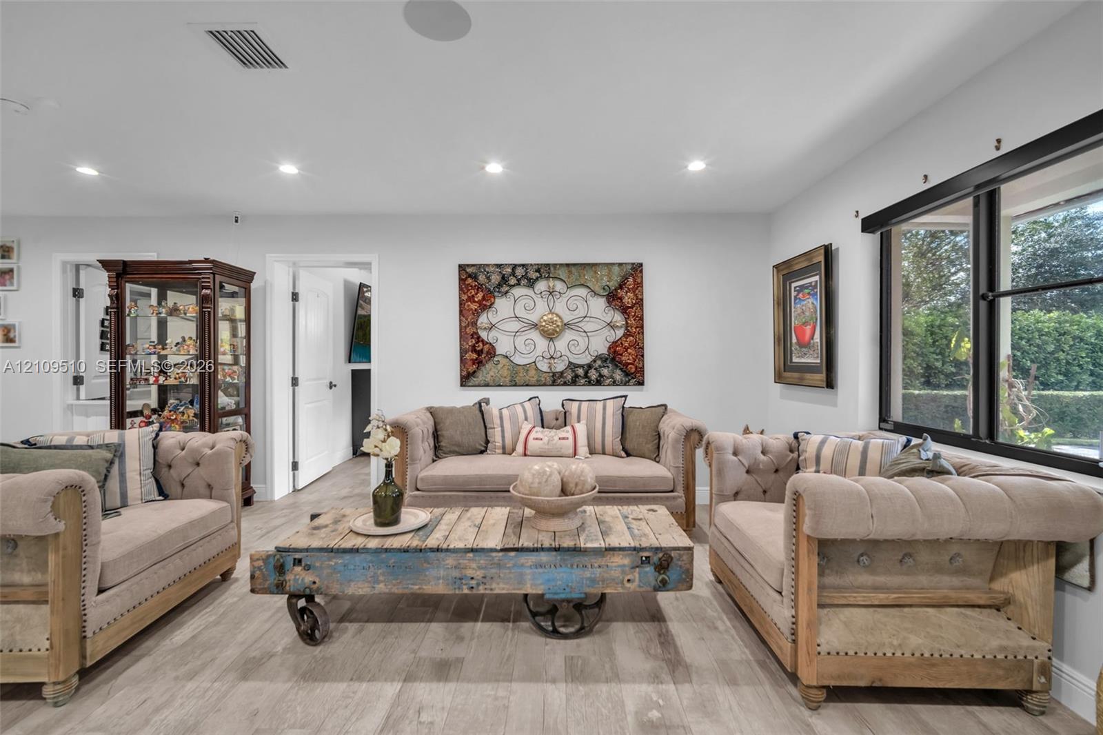 Interior space featuring wood-finish flooring, recessed lighting, and large windows with black frames Interior space featuring wood-finish flooring, recessed lighting, and large windows with black frames