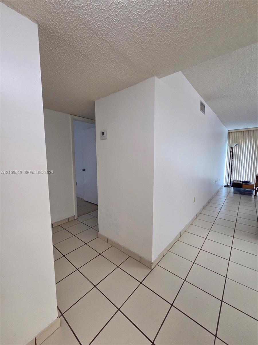 Interior area featuring neutral-toned tile flooring and vertical blinds