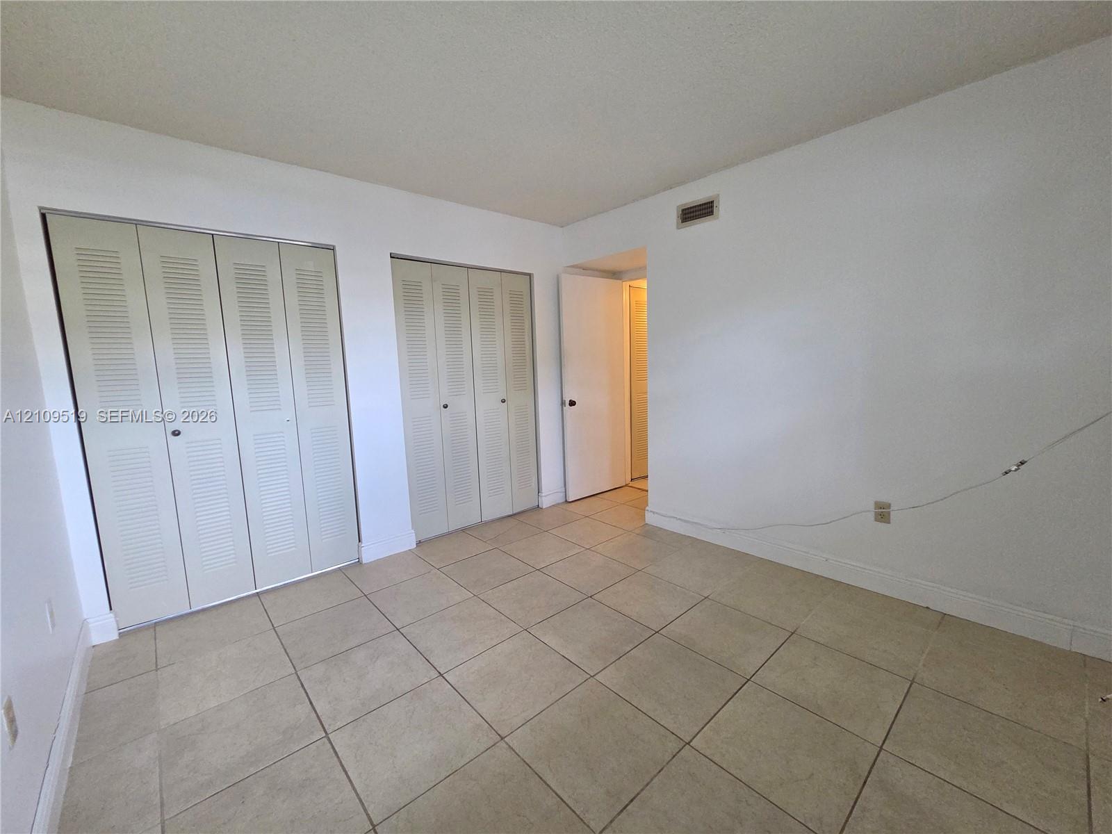 Room featuring ceramic tile flooring and two double-panel louvered closets