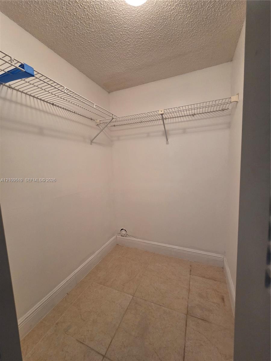 Walk-in closet offers generous storage space featuring ceramic tile flooring and white wire shelving