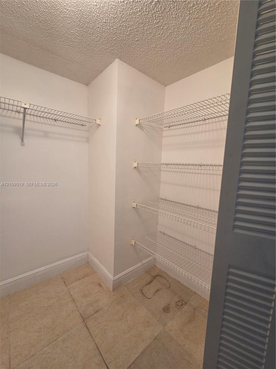 Walk-in closet generous storage area featuring tile flooring, white interior walls, and multi-level white wire shelving