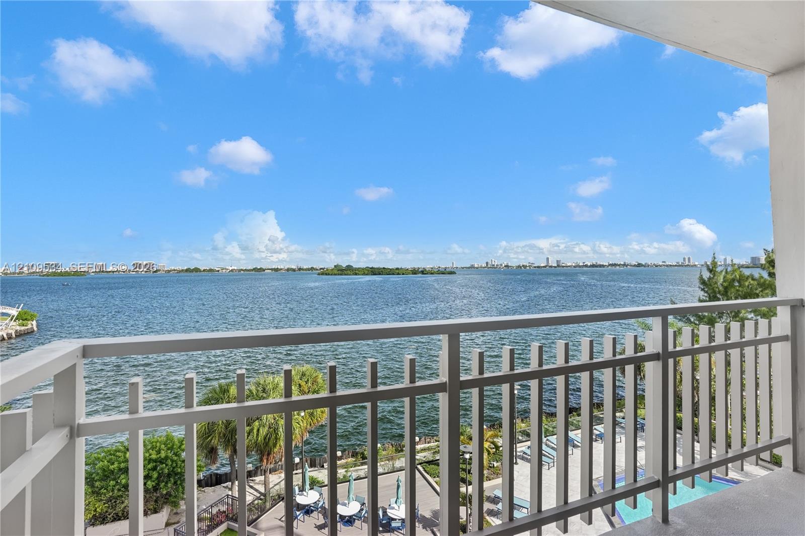 Covered balcony featuring white vertical railings and open-air exposure, overlooking expansive water scenery Covered balcony featuring white vertical railings and open-air exposure, overlooking expansive water scenery