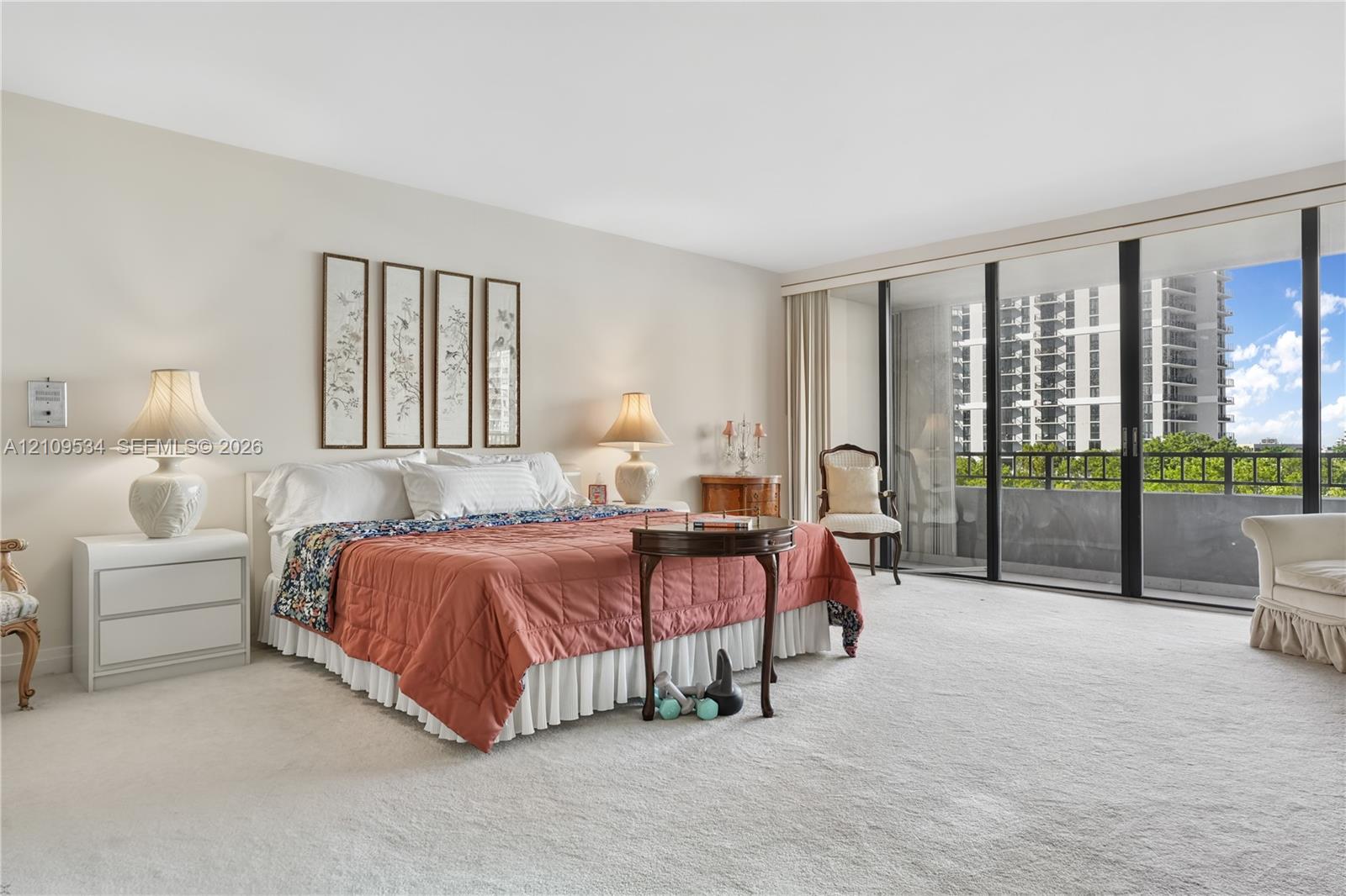Spacious room featuring neutral wall tones, floor-to-ceiling sliding glass doors, and carpeted flooring