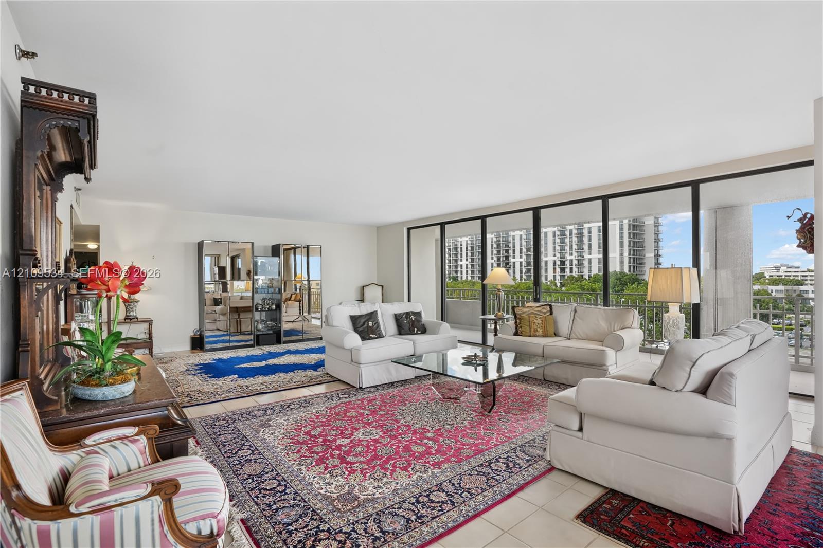 Living area featuring floor-to-ceiling glass sliding doors, neutral tile flooring, and a private balcony Living area featuring floor-to-ceiling glass sliding doors, neutral tile flooring, and a private balcony