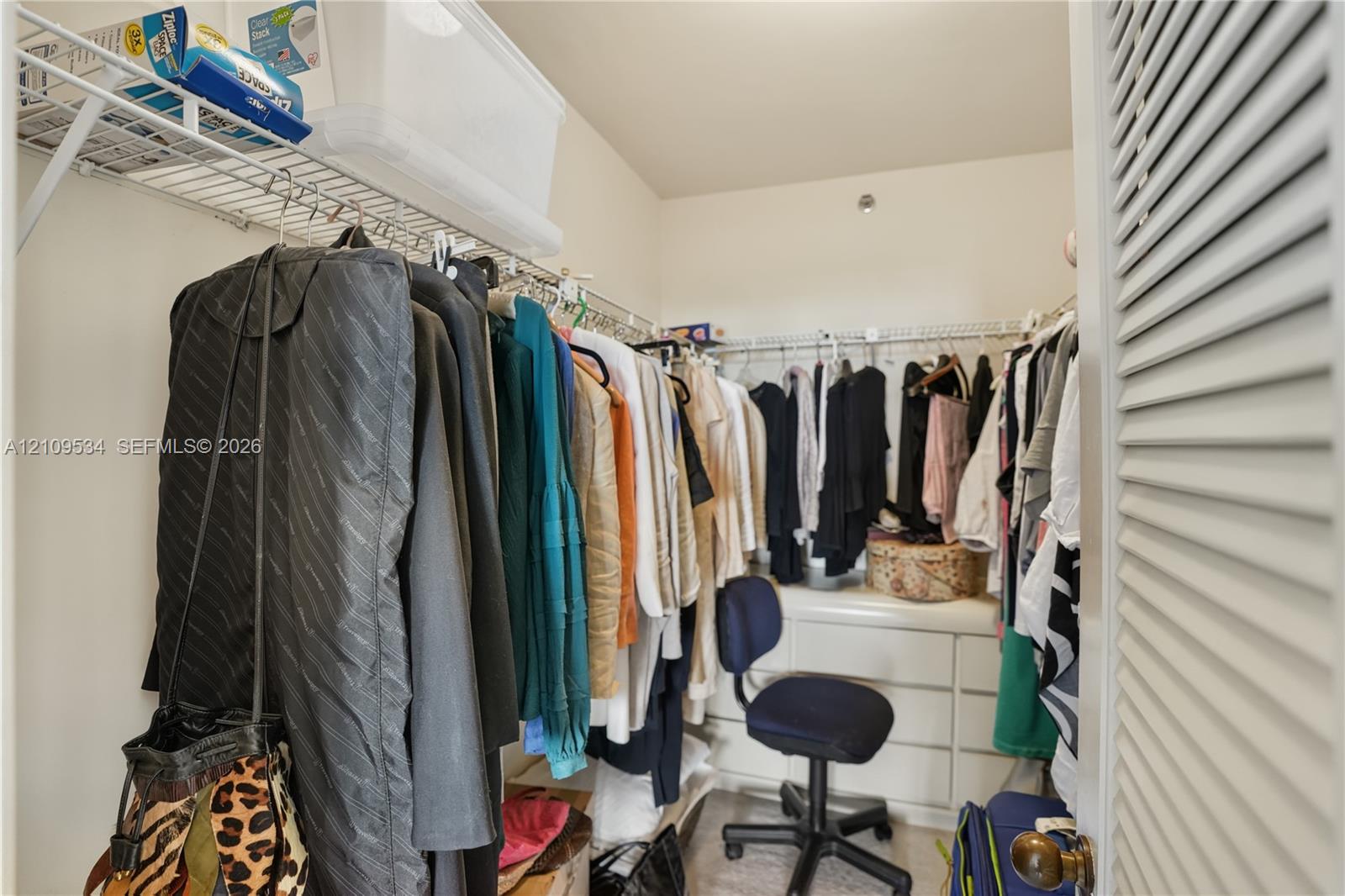 Walk-in closet featuring tiered wire shelving and built-in white cabinetry with drawers