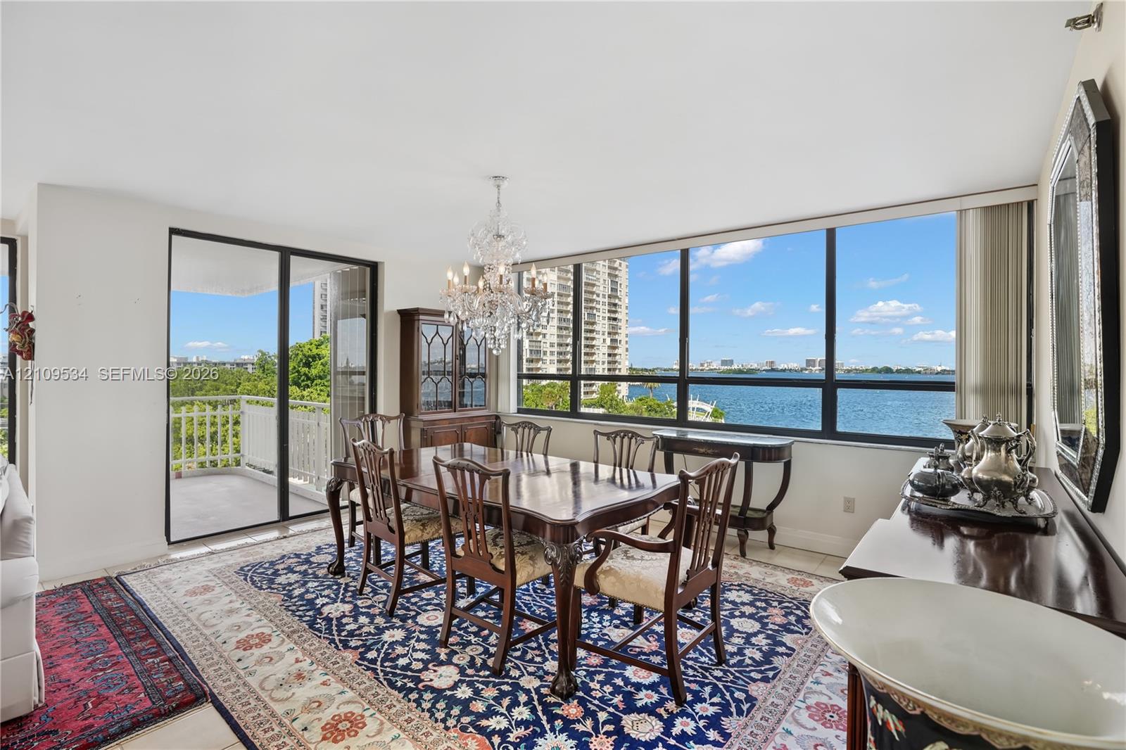 Dining area featuring floor-to-ceiling windows, porcelain tile flooring, crystal chandelier, and sliding glass doors to a private balcony Dining area featuring floor-to-ceiling windows, porcelain tile flooring, crystal chandelier, and sliding glass doors to a private balcony