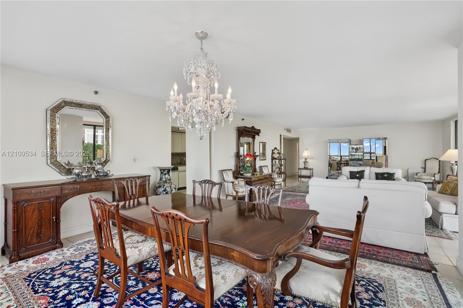Open-concept living space featuring a tiered crystal chandelier, neutral wall paint, and tile flooring Open-concept living space featuring a tiered crystal chandelier, neutral wall paint, and tile flooring