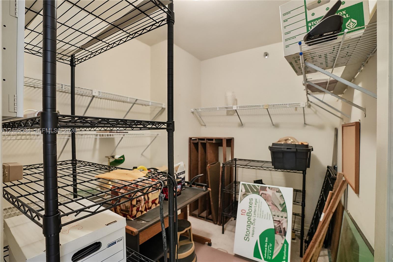 Storage area featuring white wall-mounted wire shelving and neutral wall finishes
