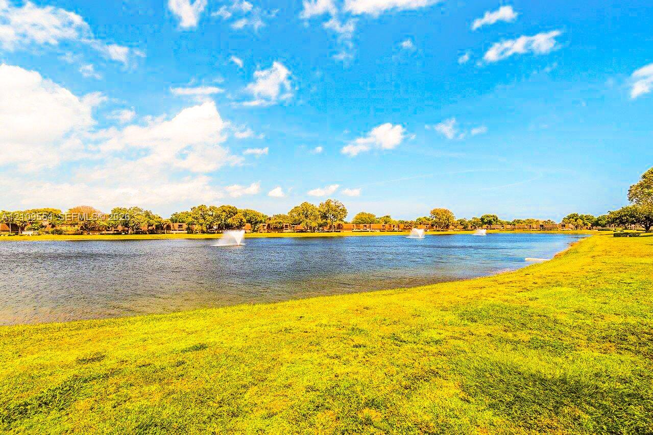 Expansive waterfront grounds featuring a manicured lawn and multi-fountain pond