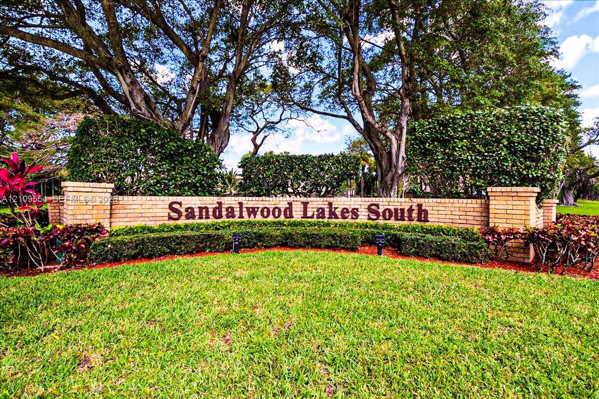 Brick monument signage featuring decorative stonework, mature trees, and manicured hedges