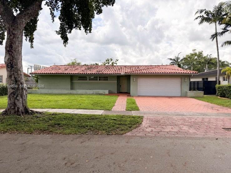 Single-story exterior featuring a clay tile roof, horizontal siding, an attached two-car garage, and a paver driveway
