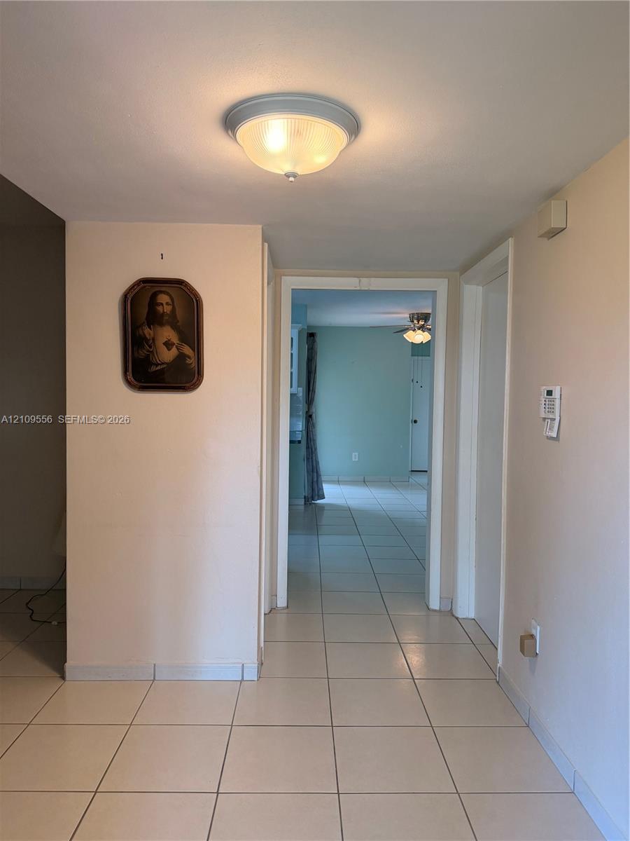 Neutral-toned interior featuring ceramic tile flooring, flush-mount ceiling lighting, and a wall-mounted security system control panel