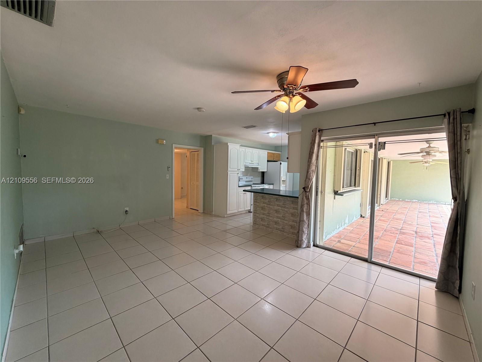 Living area featuring large format tile flooring, ceiling fan with light fixture, and floor-to-ceiling sliding glass doors