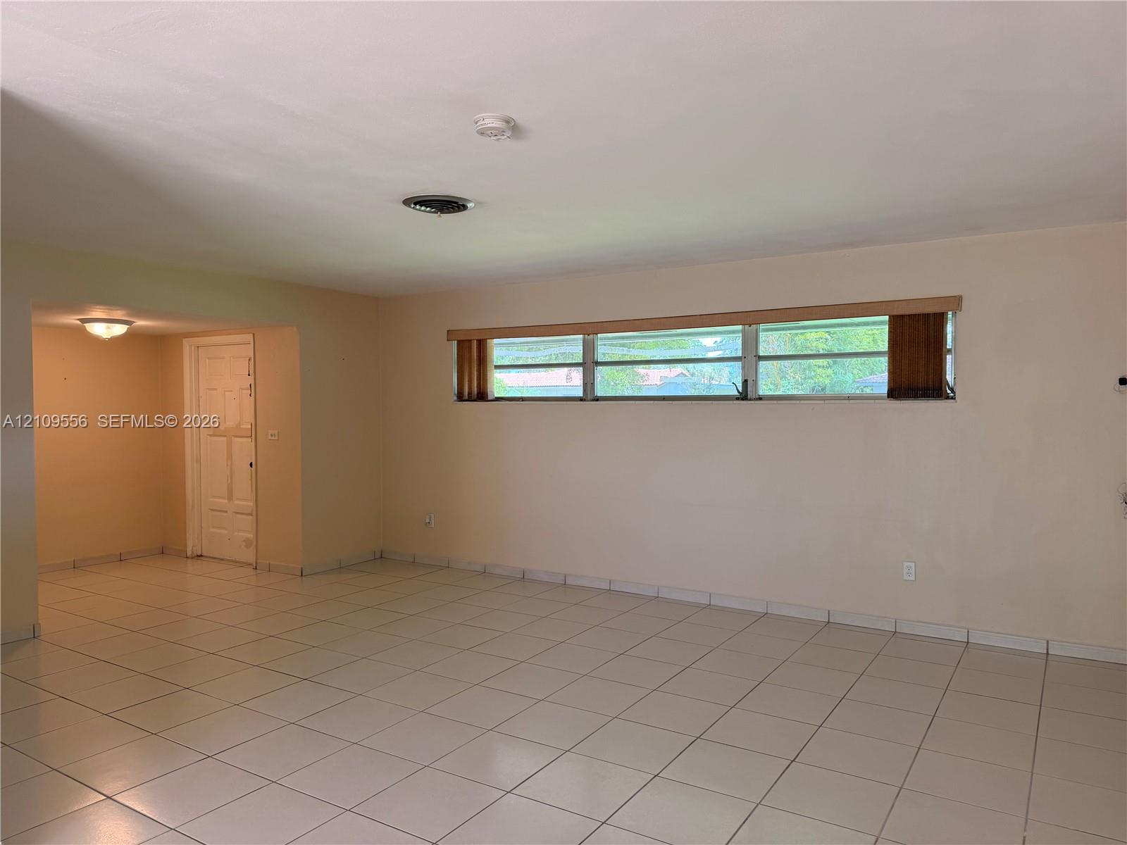 Interior space featuring neutral wall tones, ceramic tile flooring, horizontal window configuration, and recessed ceiling lighting