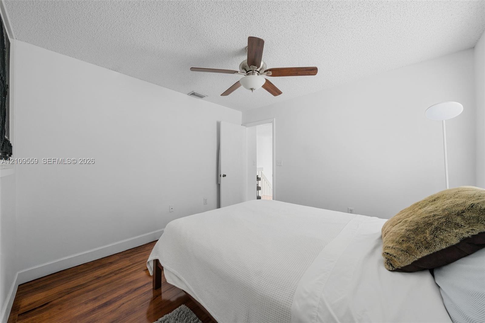 Room featuring wood-finish flooring, a ceiling fan with integrated lighting, and a neutral color palette