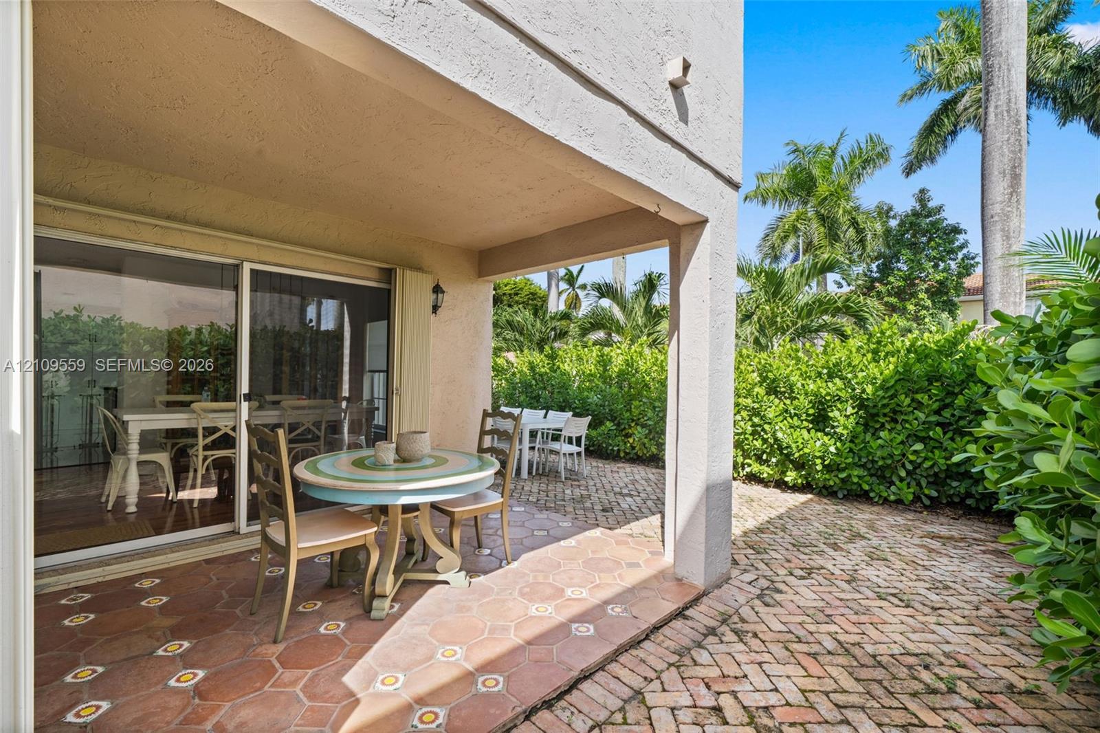 Covered terrace featuring terracotta hexagonal tile flooring, brick paver patio, and sliding glass door entry