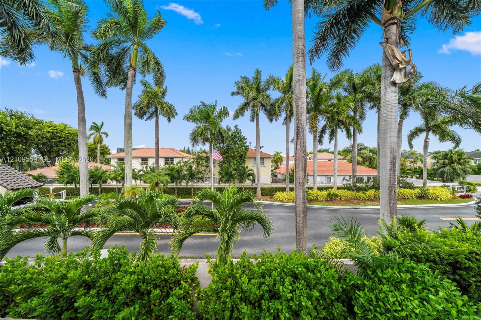 Landscaped grounds featuring mature palm trees, dense tropical shrubbery, and paved motor court