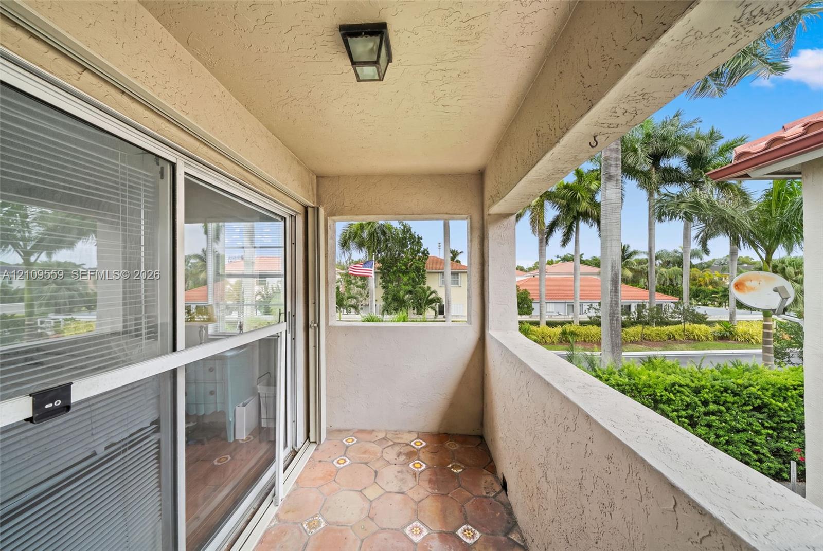 Covered balcony featuring hexagonal tile flooring, textured stucco walls, and sliding glass doors