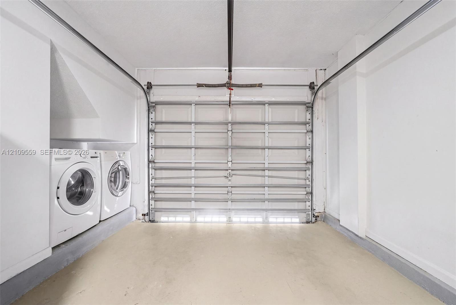 Garage featuring an overhead sectional door, concrete flooring, and built-in laundry hookups