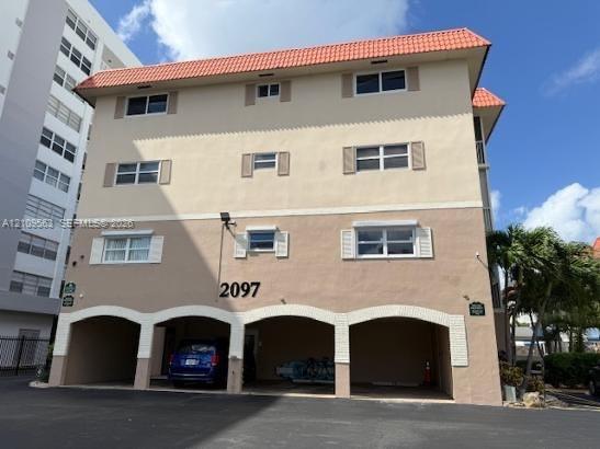 Exterior featuring a stucco facade, new roof, arched ground-level parking bays, and multi-pane windows with decorative shutters