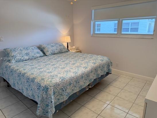 Neutral-toned room featuring large-format tile flooring and a window with an integrated roller shade