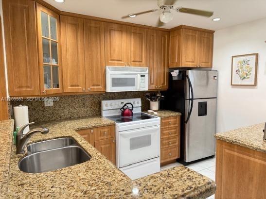 Kitchen featuring wood cabinetry, stone countertops, double-basin undermount sink, and recessed ceiling lighting.
