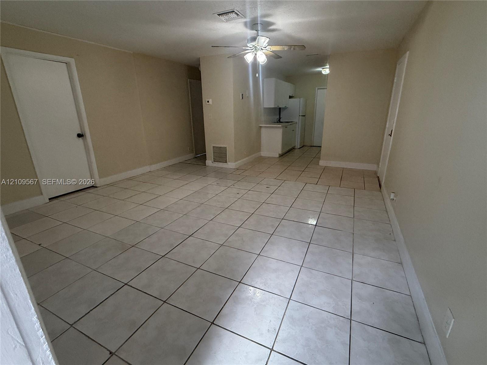 Neutral-toned interior featuring ceramic tile flooring, ceiling-mounted light fixture with fan, and white cabinetry Neutral-toned interior featuring ceramic tile flooring, ceiling-mounted light fixture with fan, and white cabinetry
