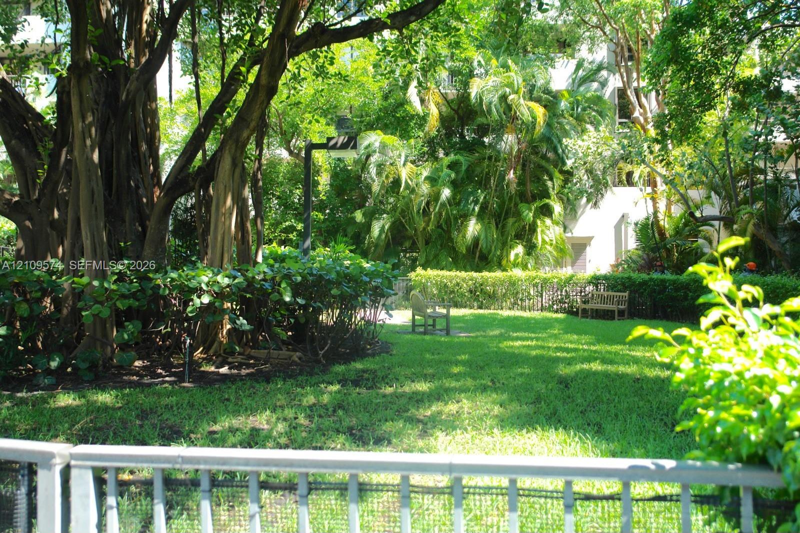 Lush outdoor grounds featuring mature trees, manicured hedges, open lawn space, and exterior lighting fixtures