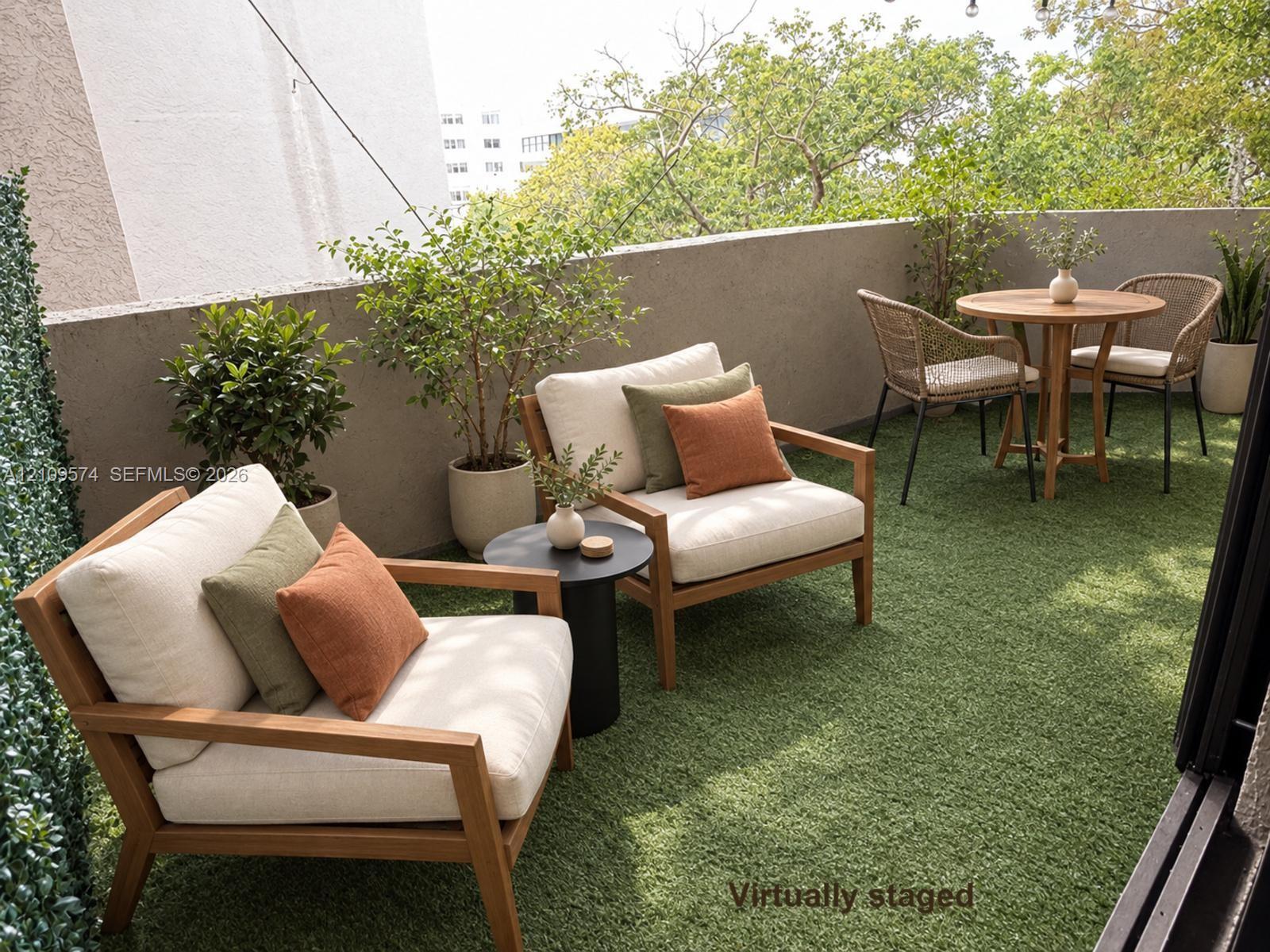 Staged Outdoor balcony featuring synthetic grass turf, solid concrete perimeter walls, and overhead string lighting Staged Outdoor balcony featuring synthetic grass turf, solid concrete perimeter walls, and overhead string lighting