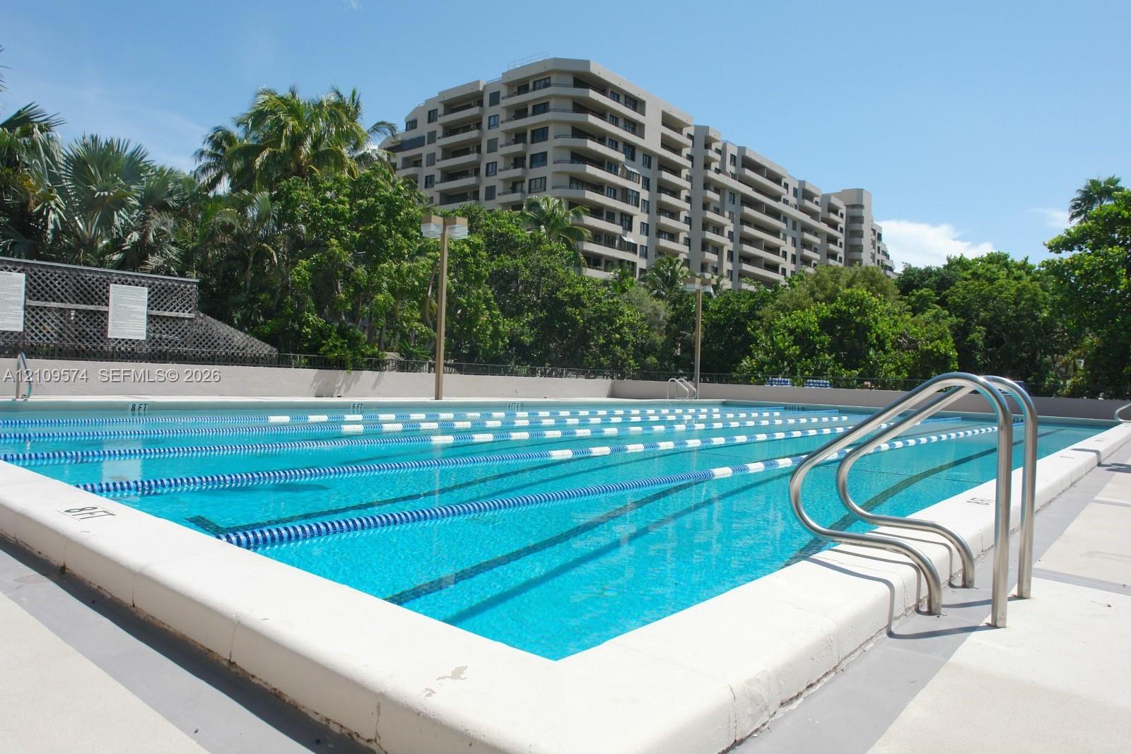 Multi-lane lap pool featuring metal entry railings, lane markers, and a concrete pool deck