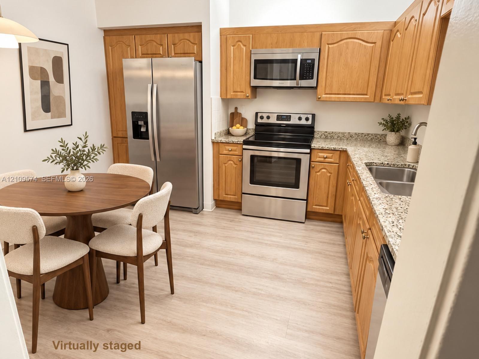 Kitchen featuring wood cabinetry, stone-finish countertops, stainless steel appliances, and light-tone wood-finish flooring Kitchen featuring wood cabinetry, stone-finish countertops, stainless steel appliances, and light-tone wood-finish flooring