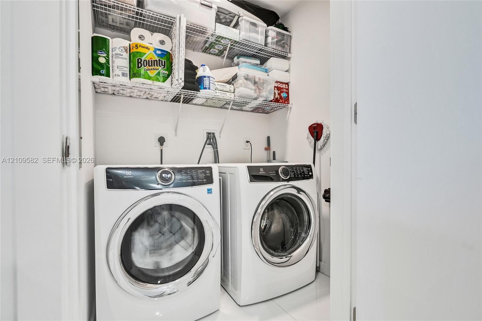 Laundry closet featuring a pair of white front-loading appliances and multi-level white wire shelving