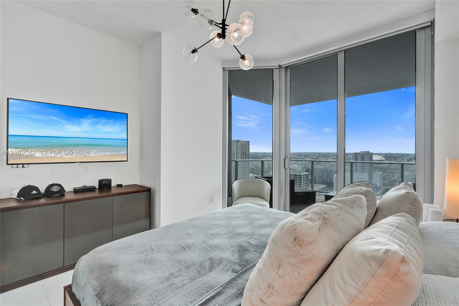 Floor-to-ceiling windows, private balcony, modern multi-arm chandelier, and built-in cabinetry