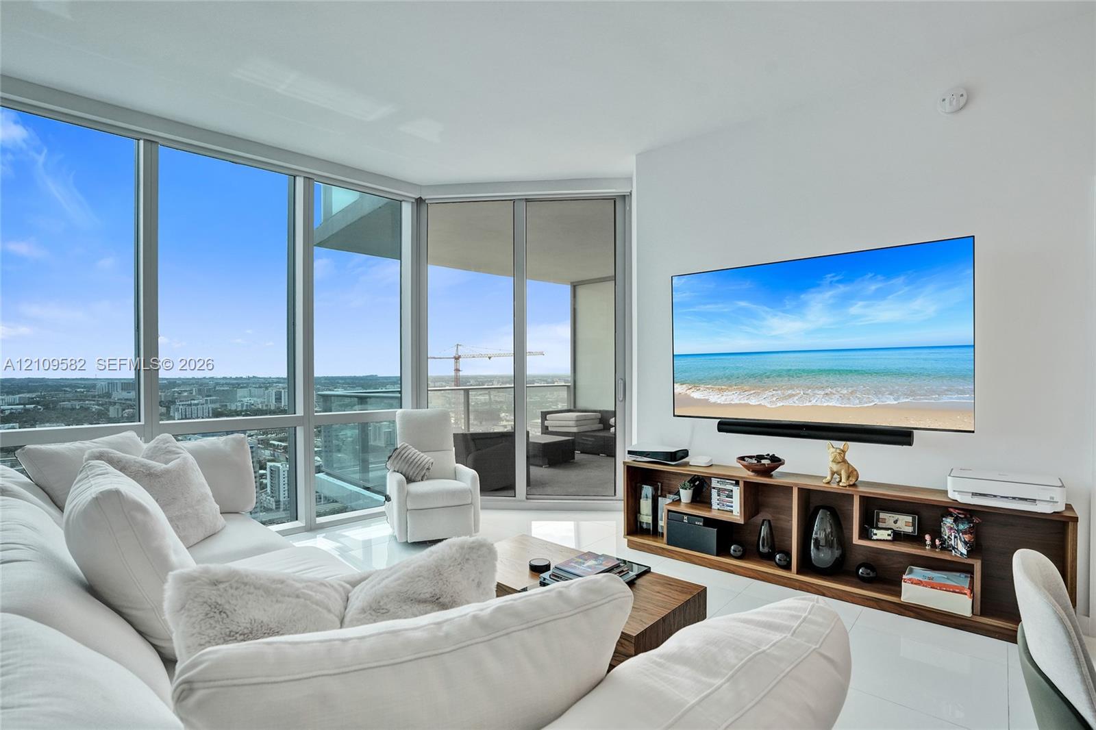 Floor-to-ceiling glass windows, expansive private balcony, and polished white tile flooring