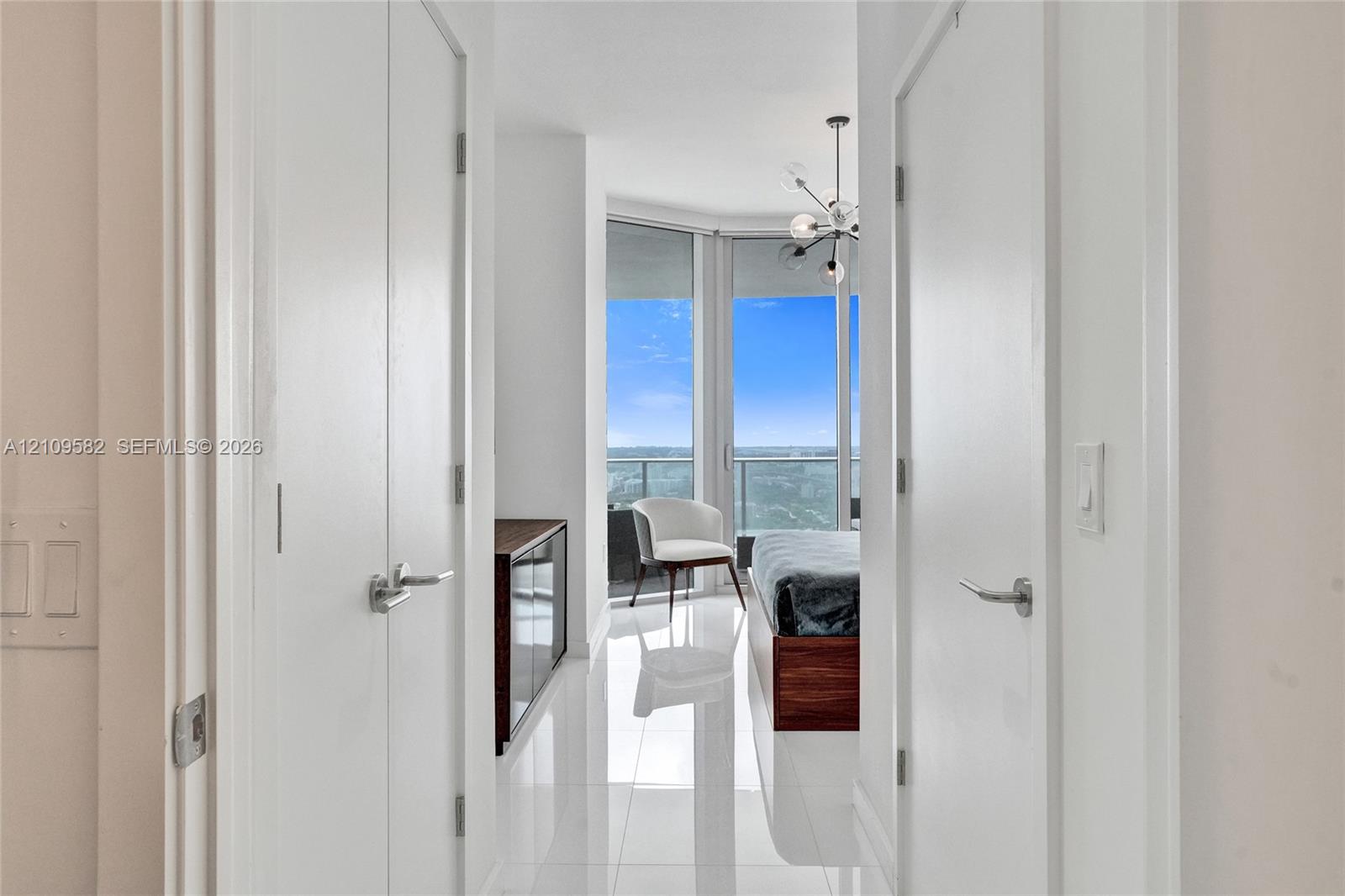 Floor-to-ceiling windows, polished tile flooring, multi-arm chandelier, and double-closet configuration