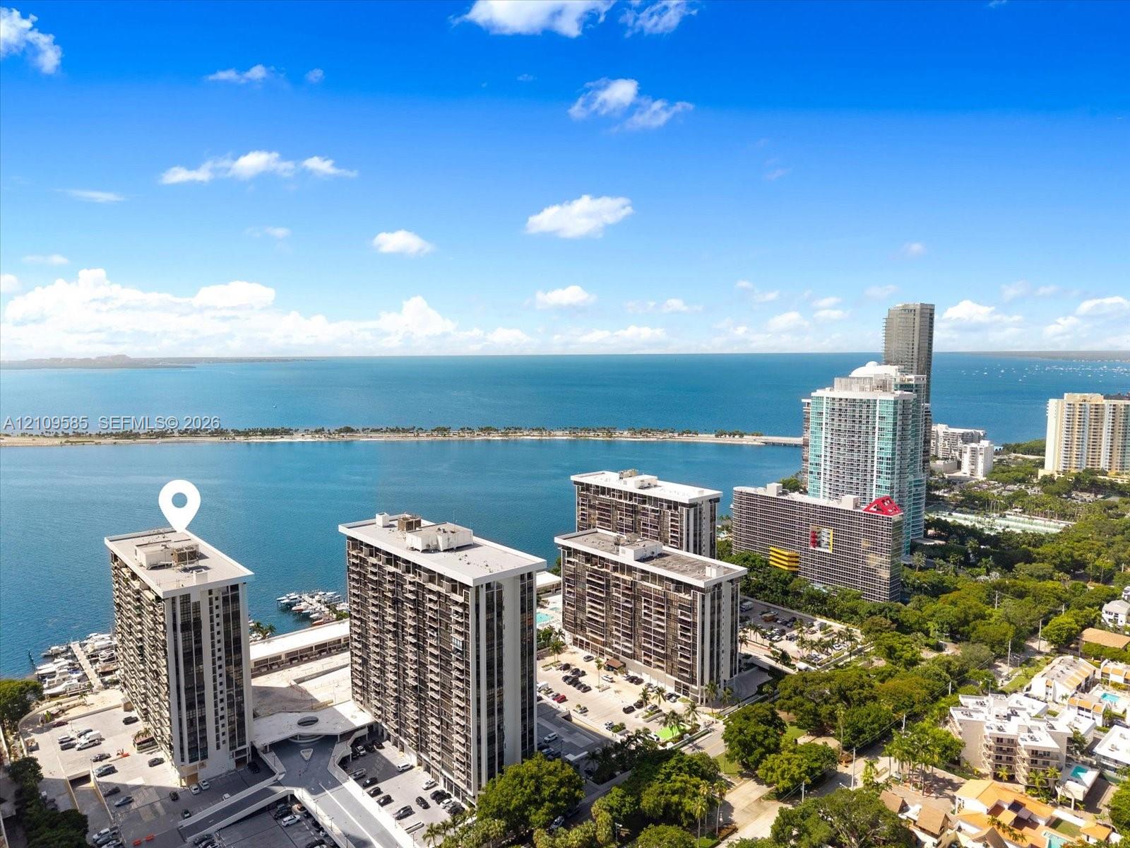 High-rise residential building featuring expansive waterfront access, an attached deep-water boat slip, and surrounding mature tree canopy