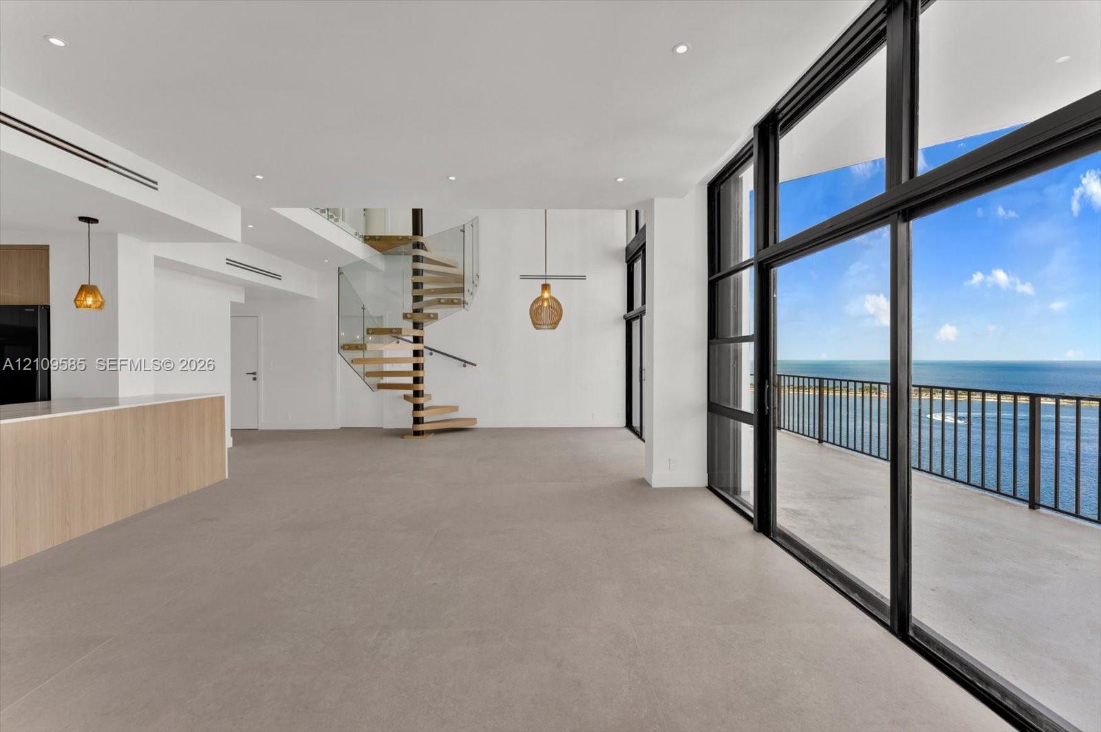 Floor-to-ceiling glass panel walls, spiral staircase with glass railing, recessed lighting, wood-finish kitchen island, and private balcony
