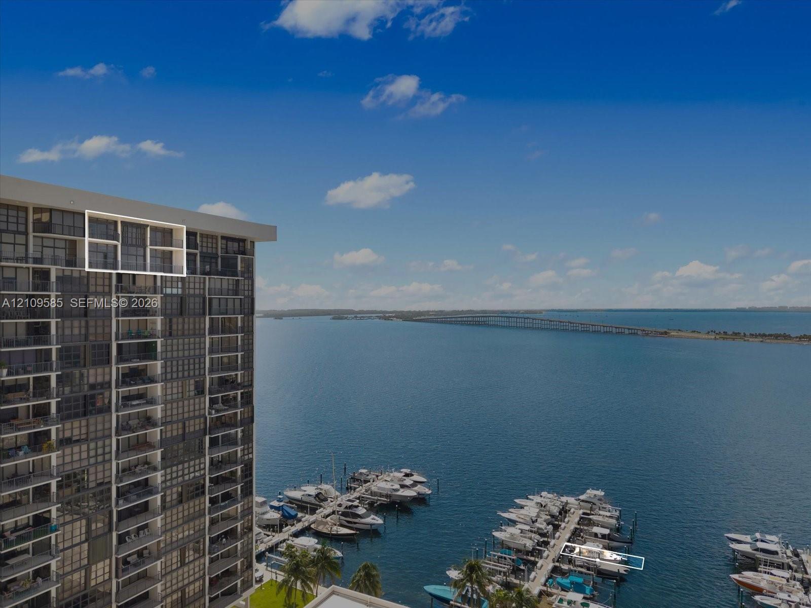 High-rise residential exterior with glass-panel balconies, featuring direct water access to a private marina and spanning water backdrop