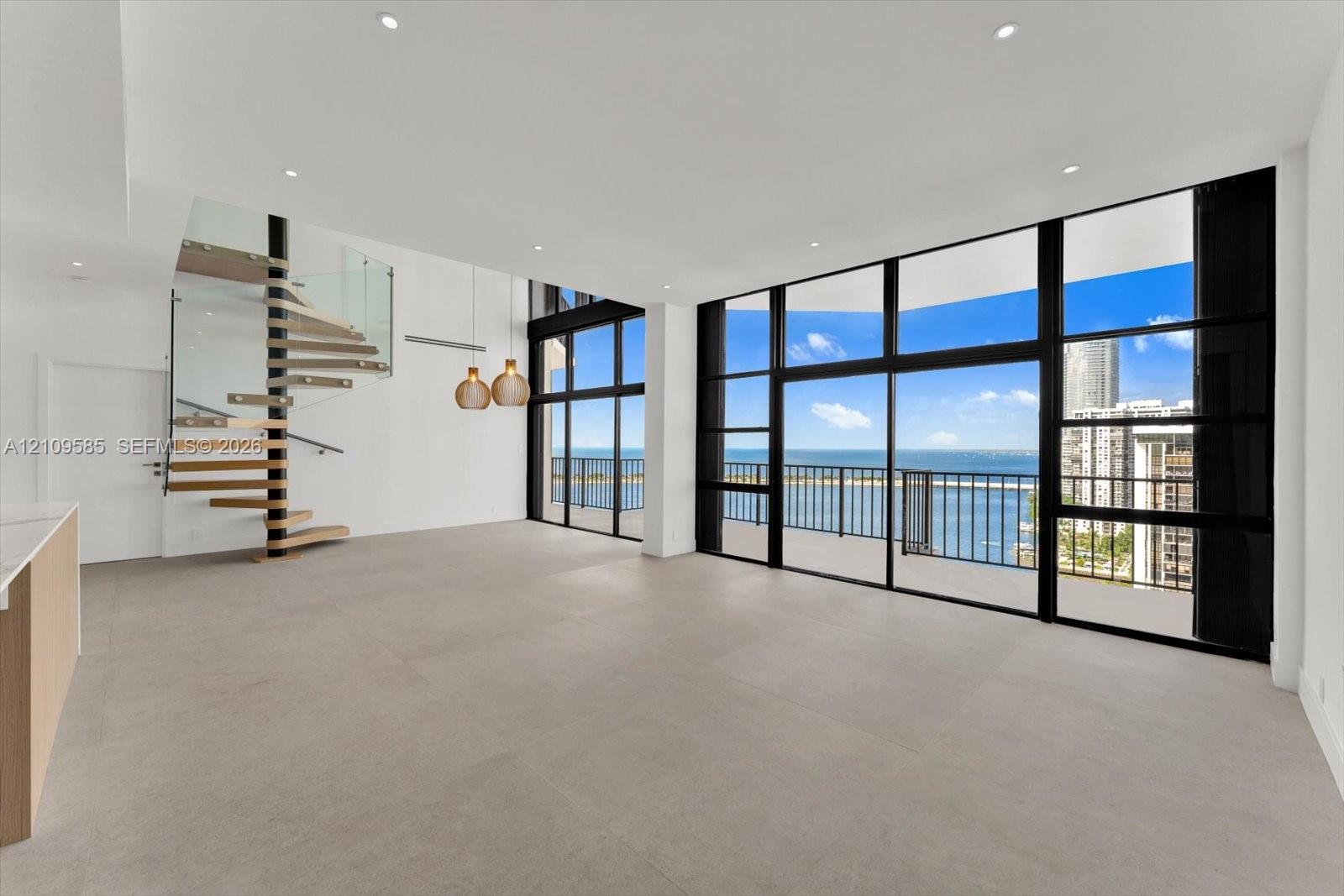 Open-concept interior featuring floor-to-ceiling windows, spiral staircase with glass railing, large-format tile flooring, and recessed lighting