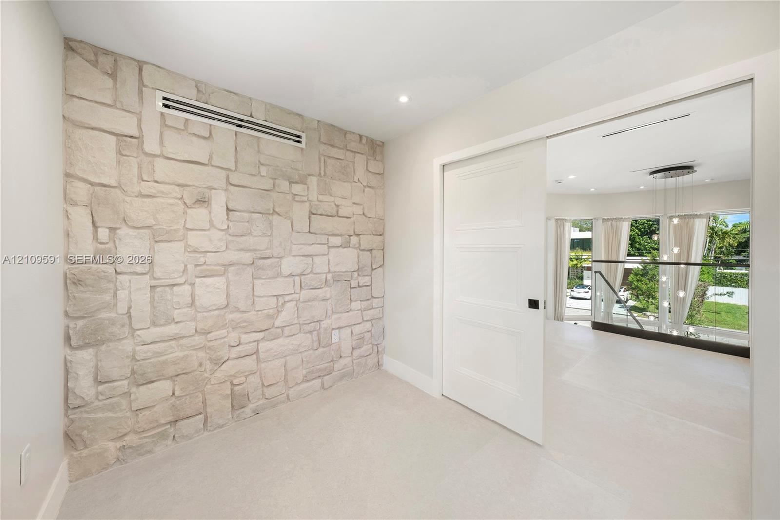 Textured stone feature wall with recessed lighting and three-panel solid core sliding door