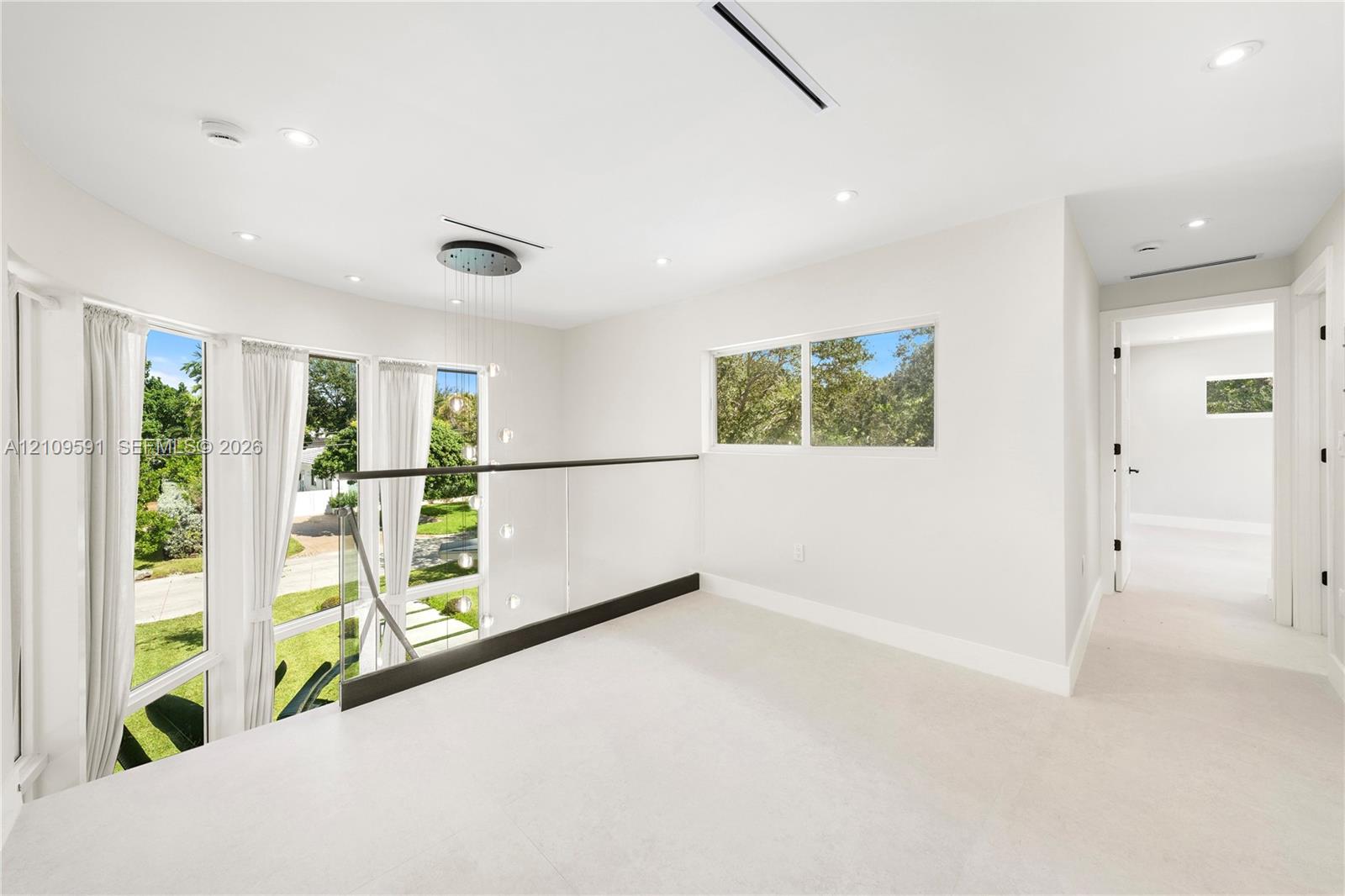 Open-concept landing featuring floor-to-ceiling windows, glass paneled railing, recessed lighting, and a multi-tiered pendant fixture