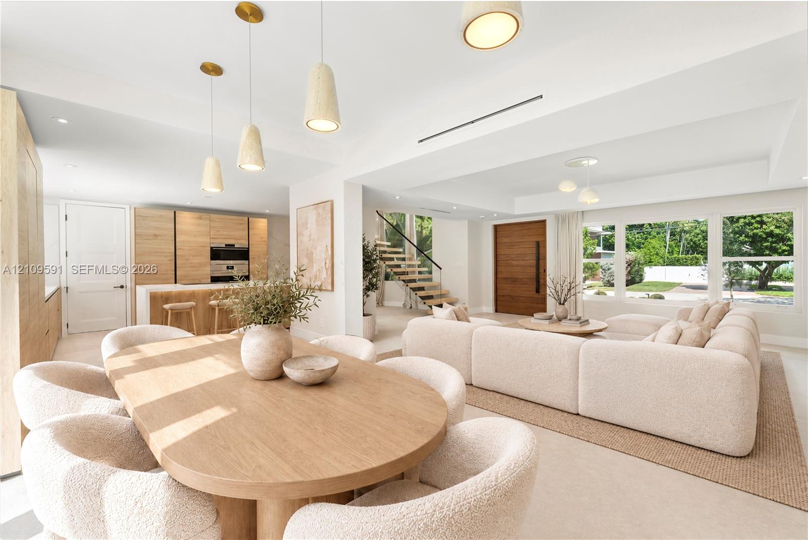 Virtually Staged: Open-concept interior featuring light wood-finish cabinetry, a floating staircase with glass railing, recessed lighting, pendant fixtures, and large picture windows