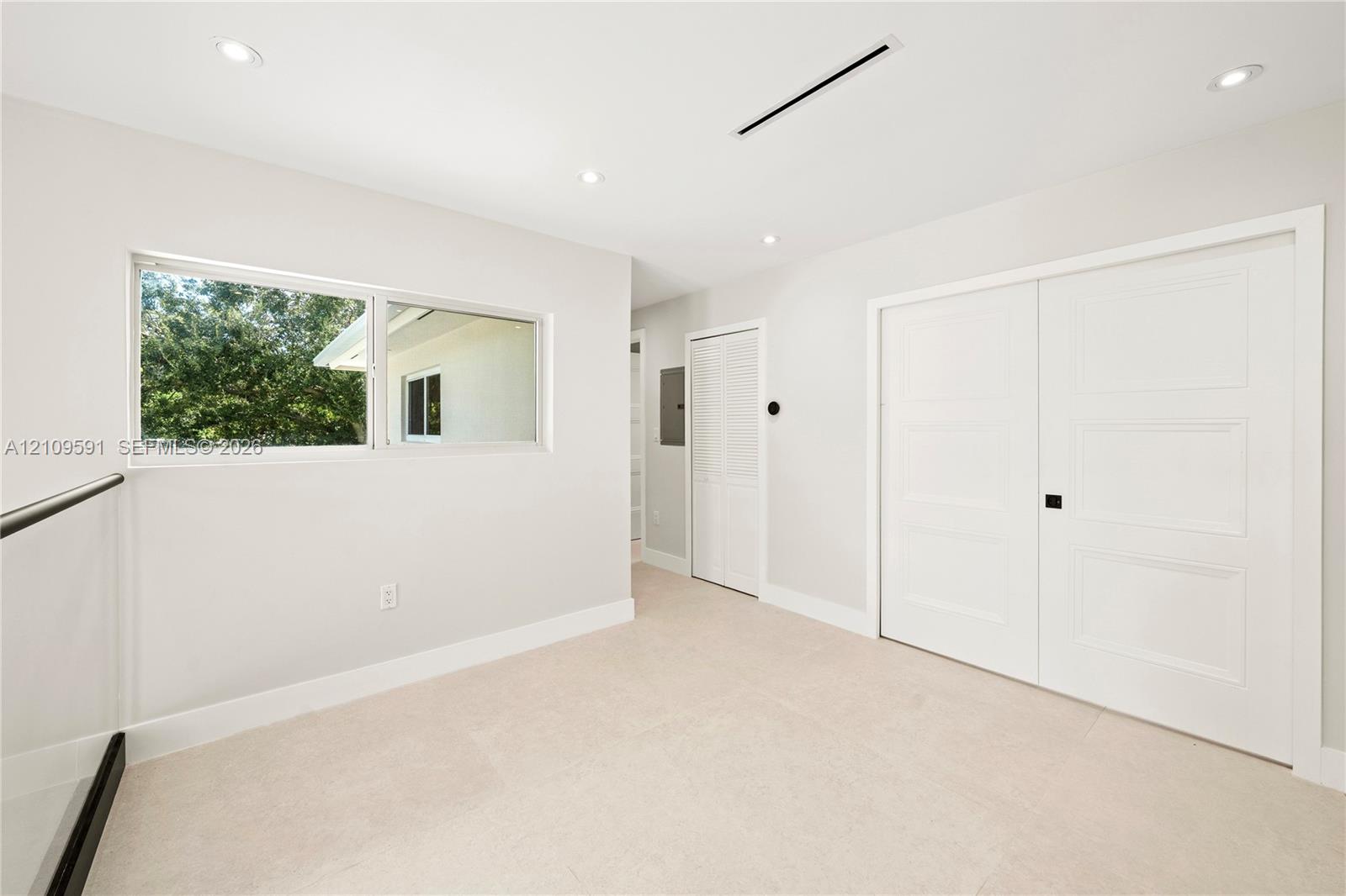 Neutral-toned interior featuring recessed lighting, a horizontal window, wall-to-wall carpeting, and double doors with matte black hardware