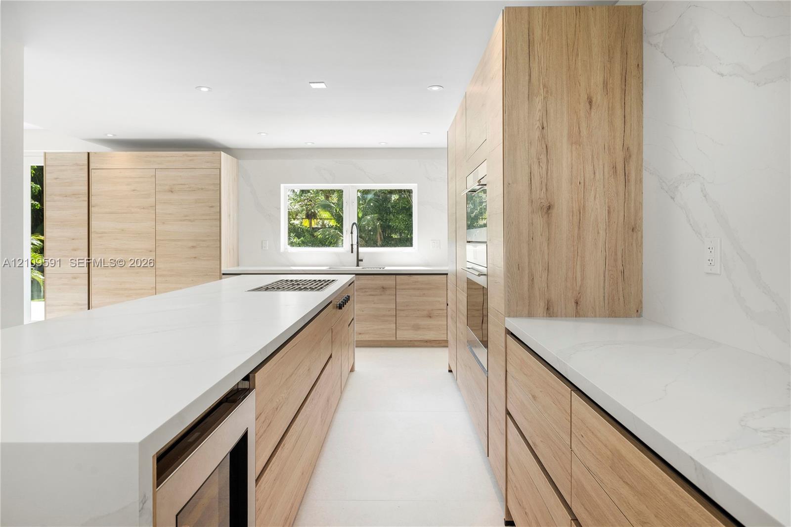 Kitchen featuring light wood-finish cabinetry, quartz countertops with full-height backsplash, a large center island, built-in stainless steel appliances, and recessed lighting