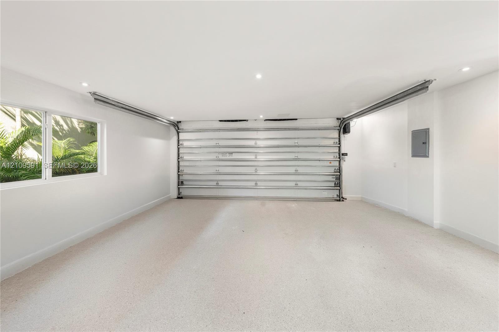 Finished interior garage space featuring recessed lighting, a smooth-finish floor, a multi-panel overhead door, and a side window providing natural light