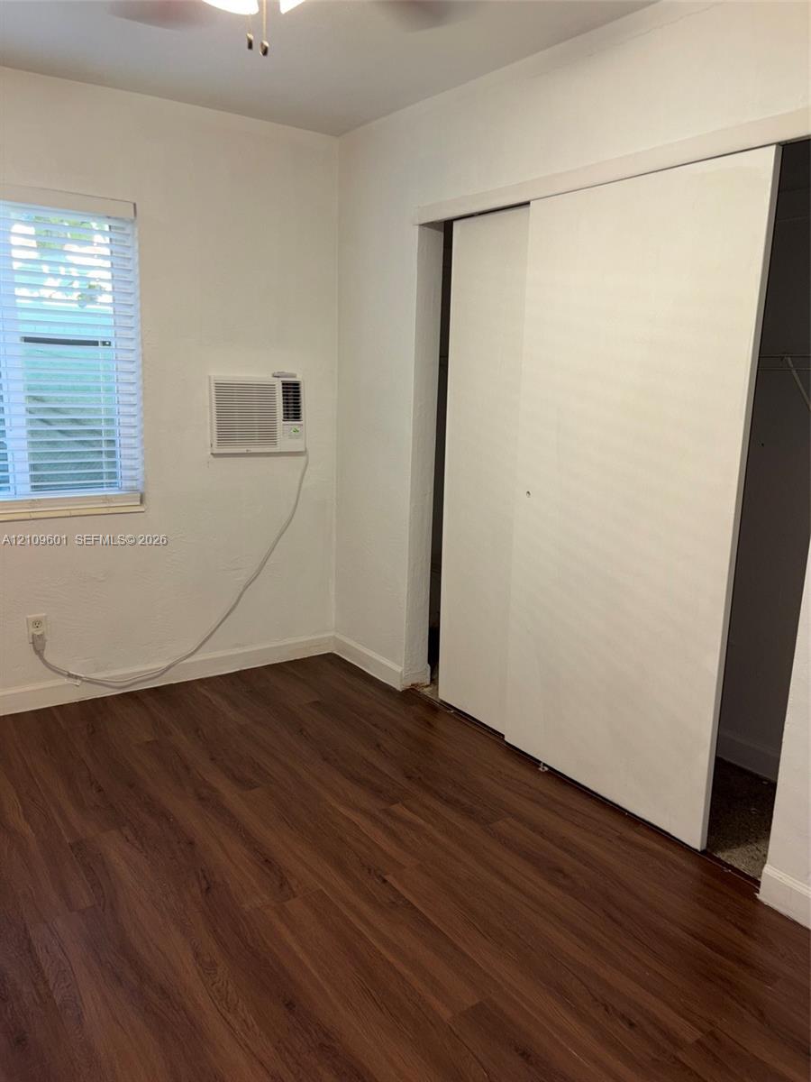 Wood-finish flooring, sliding closet doors, wall-mounted air conditioning unit, and horizontal window blinds